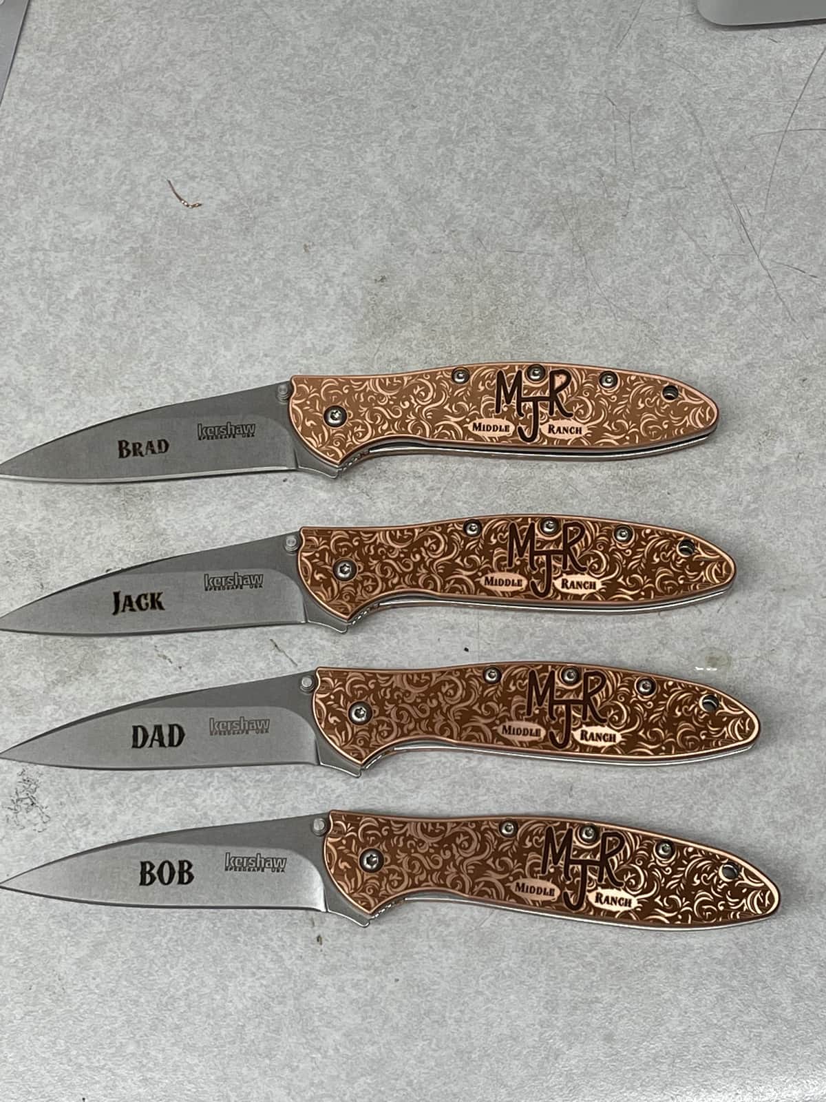 Custom name engraving with intricate decorative pattern on four Kershaw knives